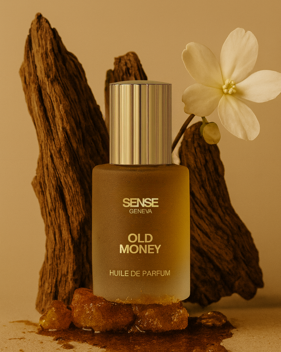 Flacon d’huile de parfum Sense Geneva Old Money posé sur des morceaux de résine, devant du bois de oud et une fleur de jasmin blanc.