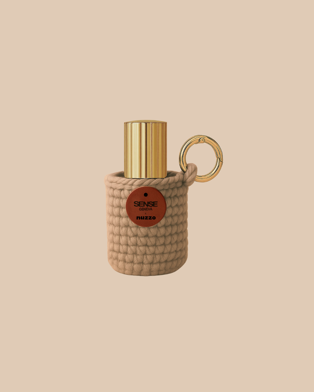Étui porte-parfum Sense Geneva tricoté de couleur beige, contenant un petit flacon à capot doré et accroché à un anneau métallique doré, présenté sur un fond beige uni.