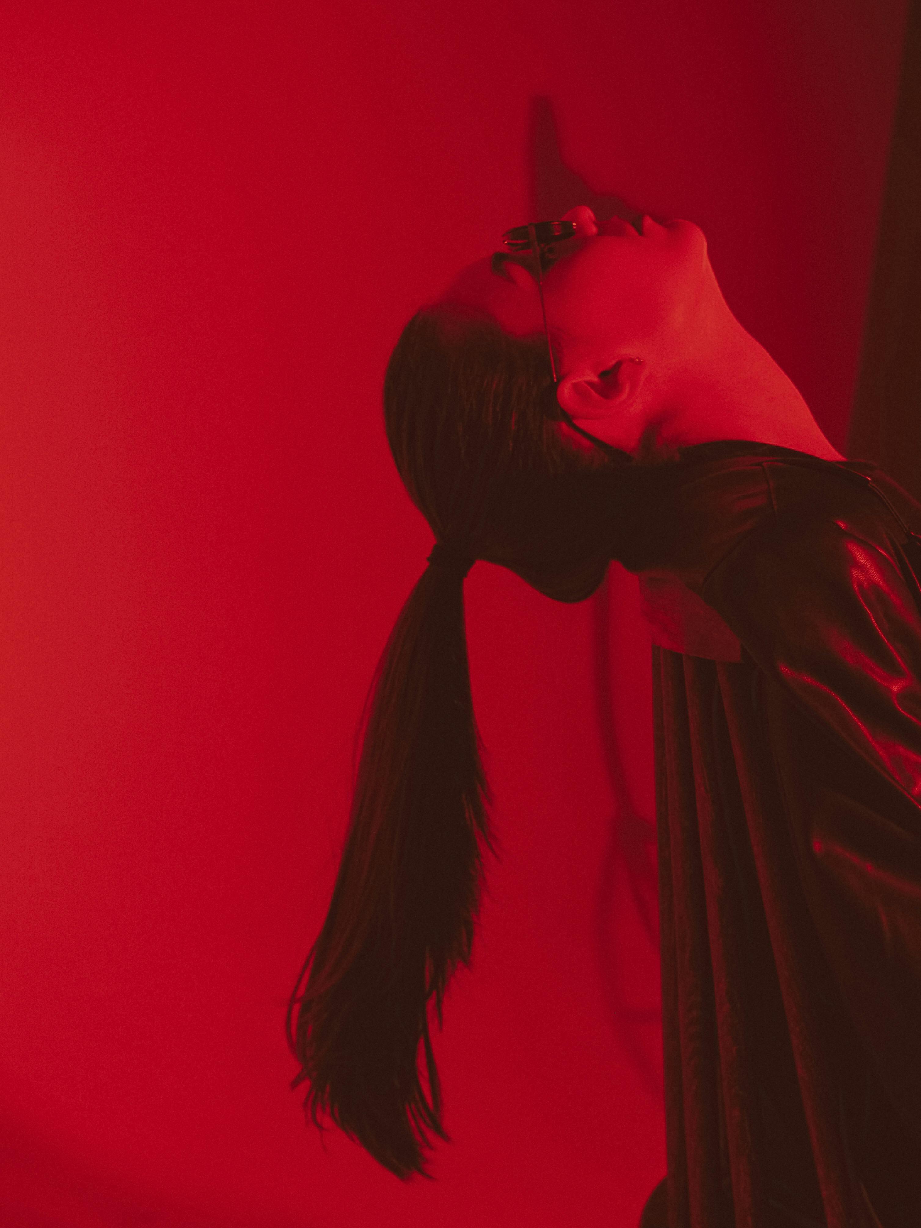 Femme penchant la tête en arrière sur un fond rouge.