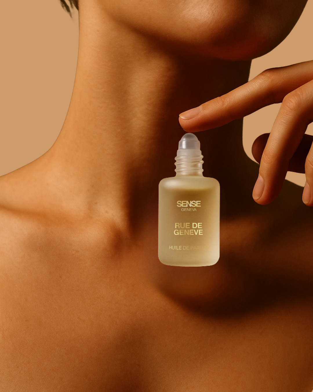 Flacon d’huile de parfum Rue de Genève appliqué au roll-on sur la peau nue du cou, avec un doigt effleurant l’embout, dans une lumière chaude et minimaliste.
